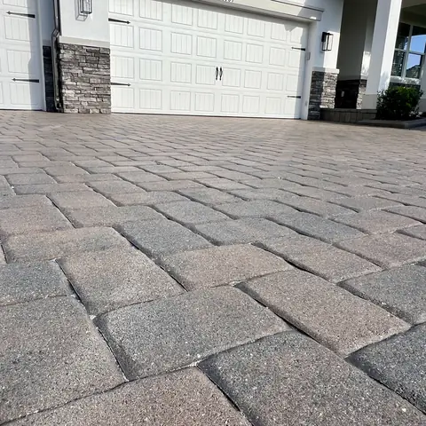 Large paver driveway sealed in front of a garage
